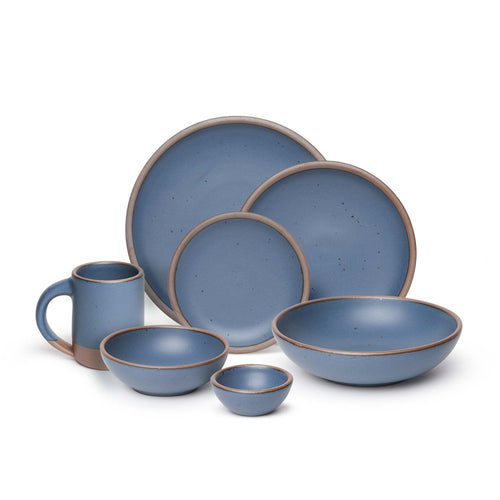 The Mug, bitty bowl, breakfast bowl, everyday bowl, cake plate, side plate and dinner plate paired together in a cool, medium blue color featuring iron speckles