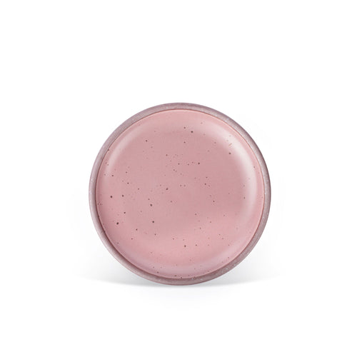 A medium sized ceramic plate in a dusty mauve pink color featuring iron speckles and an unglazed rim.