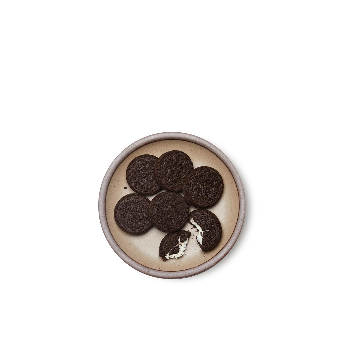 Oreos on a dessert sized ceramic plate in a warm pale brown color featuring iron speckles and an unglazed rim.
