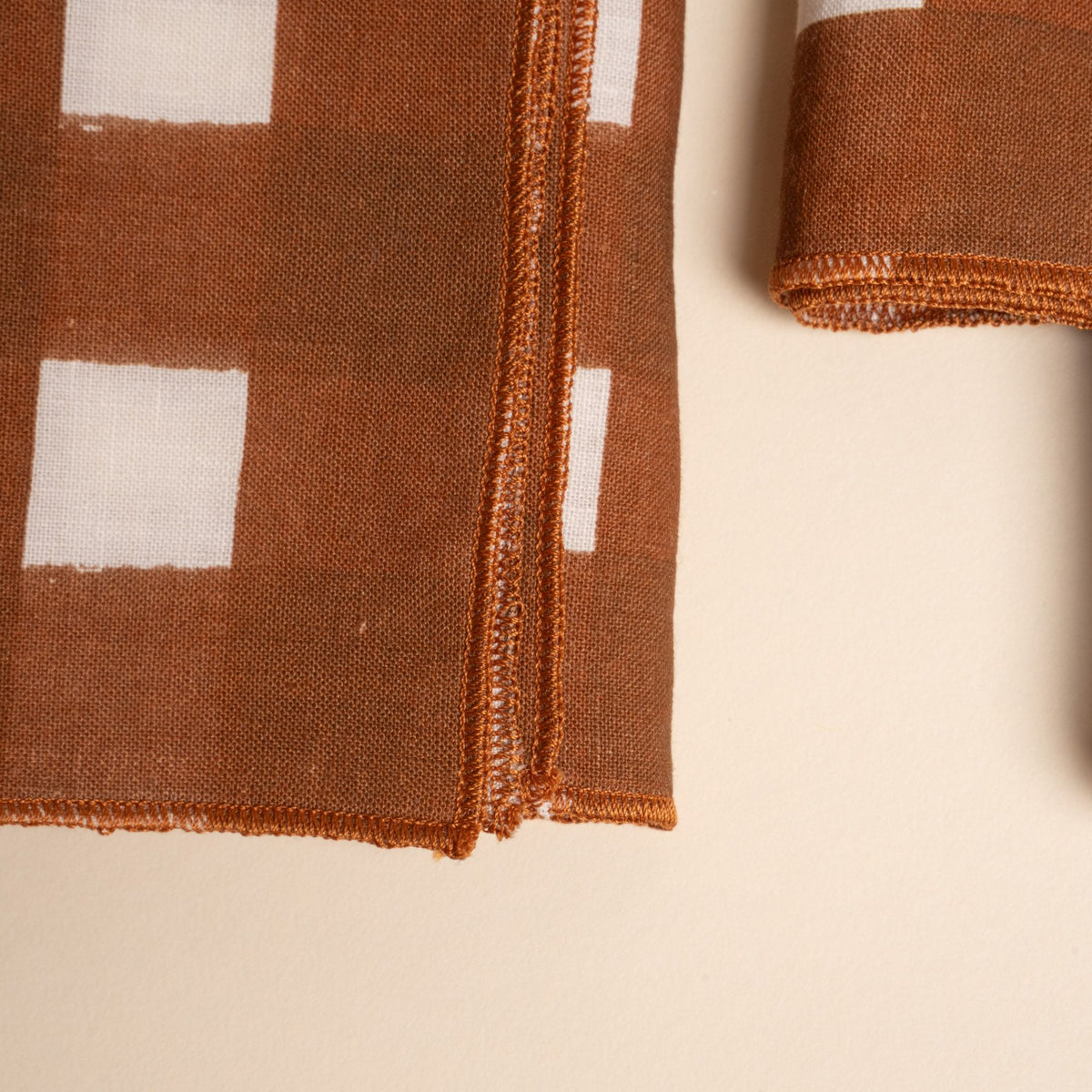 A closeup of a corner of brown and white crosshatch pattern napkins