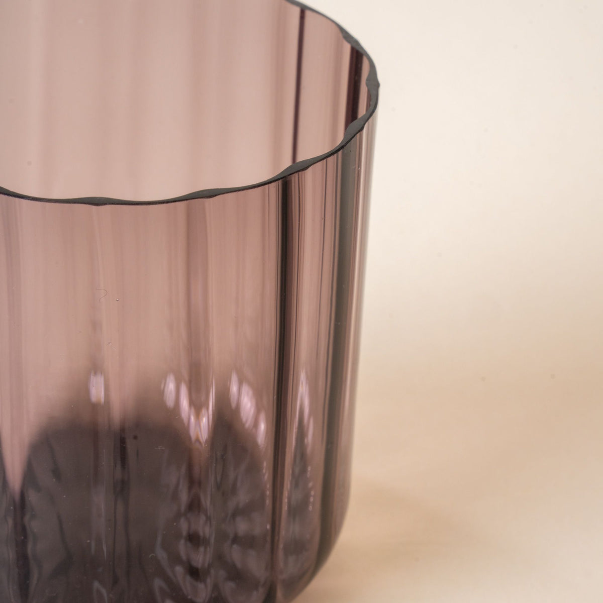 A close up of a hand holds a fluted walled tumbler in a grey purple color