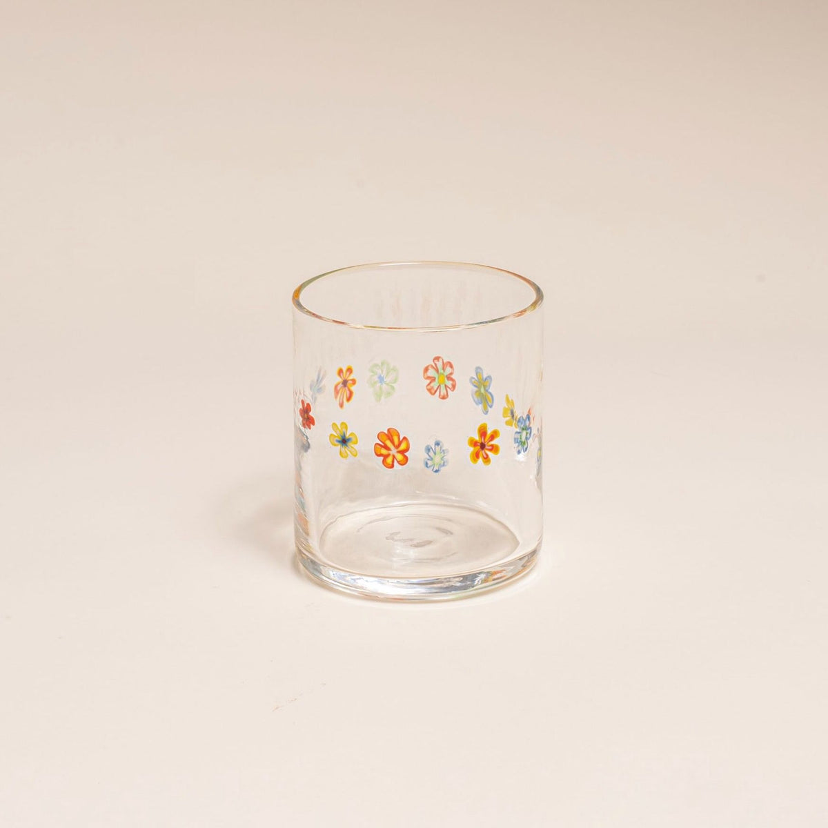 Clear glass with a ring of multicolored little flowers on a cream background.
