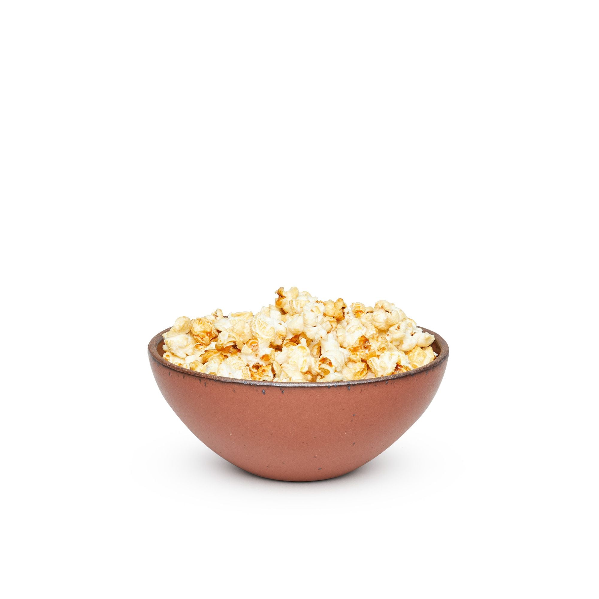 A medium rounded ceramic bowl in a cool burnt terracotta color featuring iron speckles and an unglazed rim, filled with popcorn
