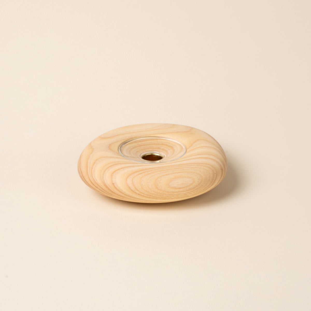 Large round light wood candle holder with visible grain and a glass insert in the center, displayed against a neutral background.