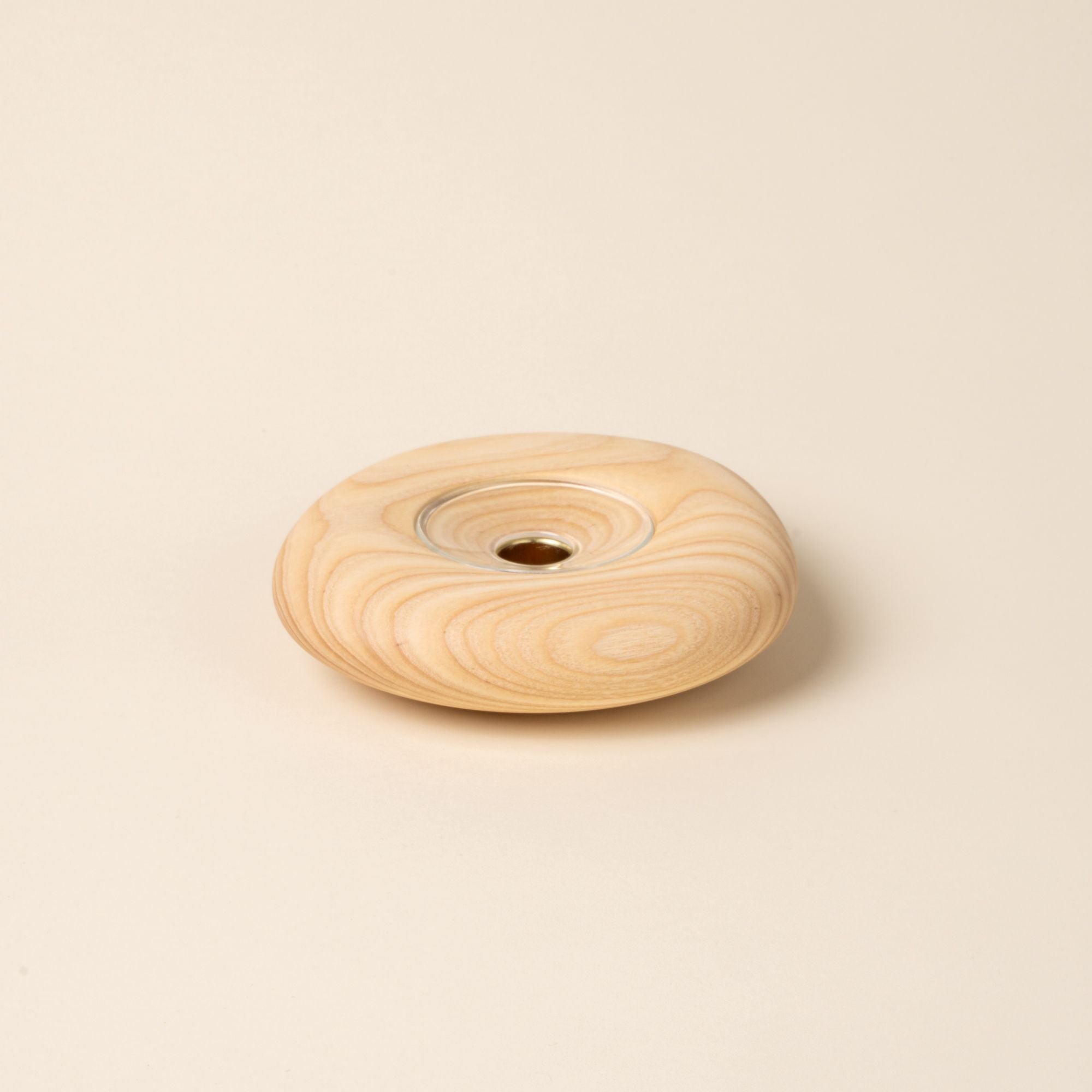 Large round light wood candle holder with visible grain and a glass insert in the center, displayed against a neutral background.