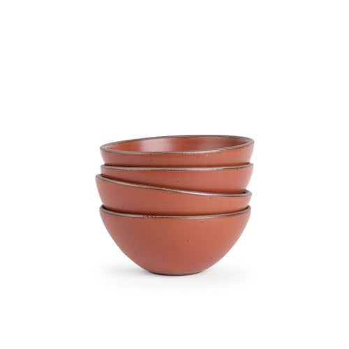 A stack of 4 medium rounded ceramic bowls in a cool burnt terracotta color featuring iron speckles and an unglazed rim