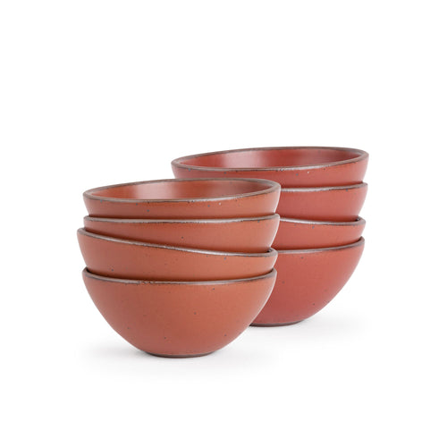 A stack of 8 medium rounded ceramic bowls in a cool burnt terracotta color featuring iron speckles and an unglazed rim