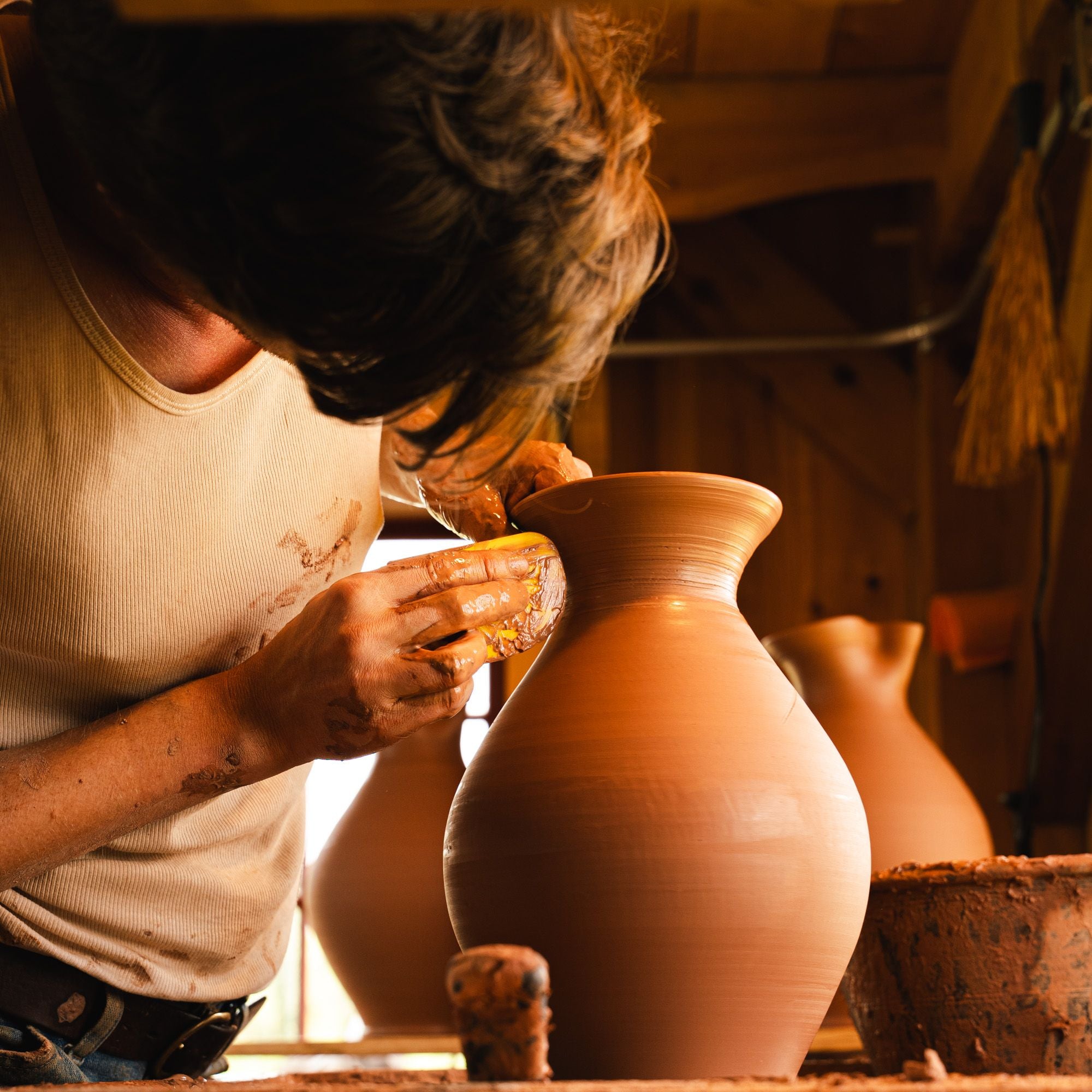 A closeup of John forming a Pitcher on the wheel.