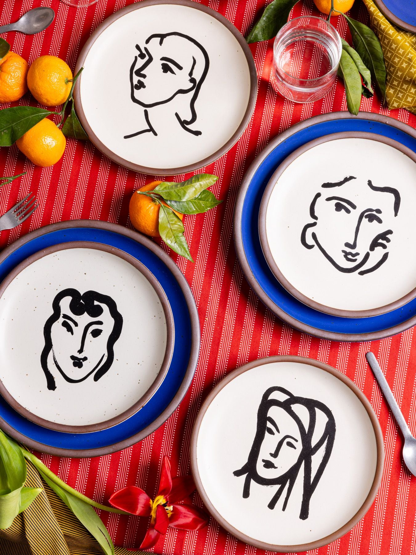 A person holds a stack of white ceramic dinner plates, topped with herbs and a whole garlic.
