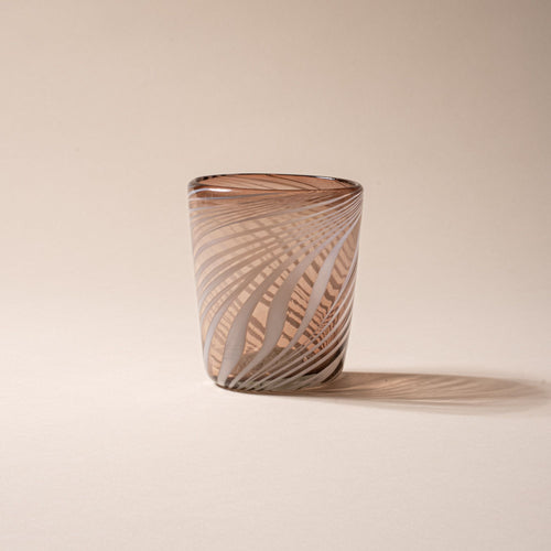 Smoky brown glass tumbler with white diagonal swirl pattern on a neutral background.