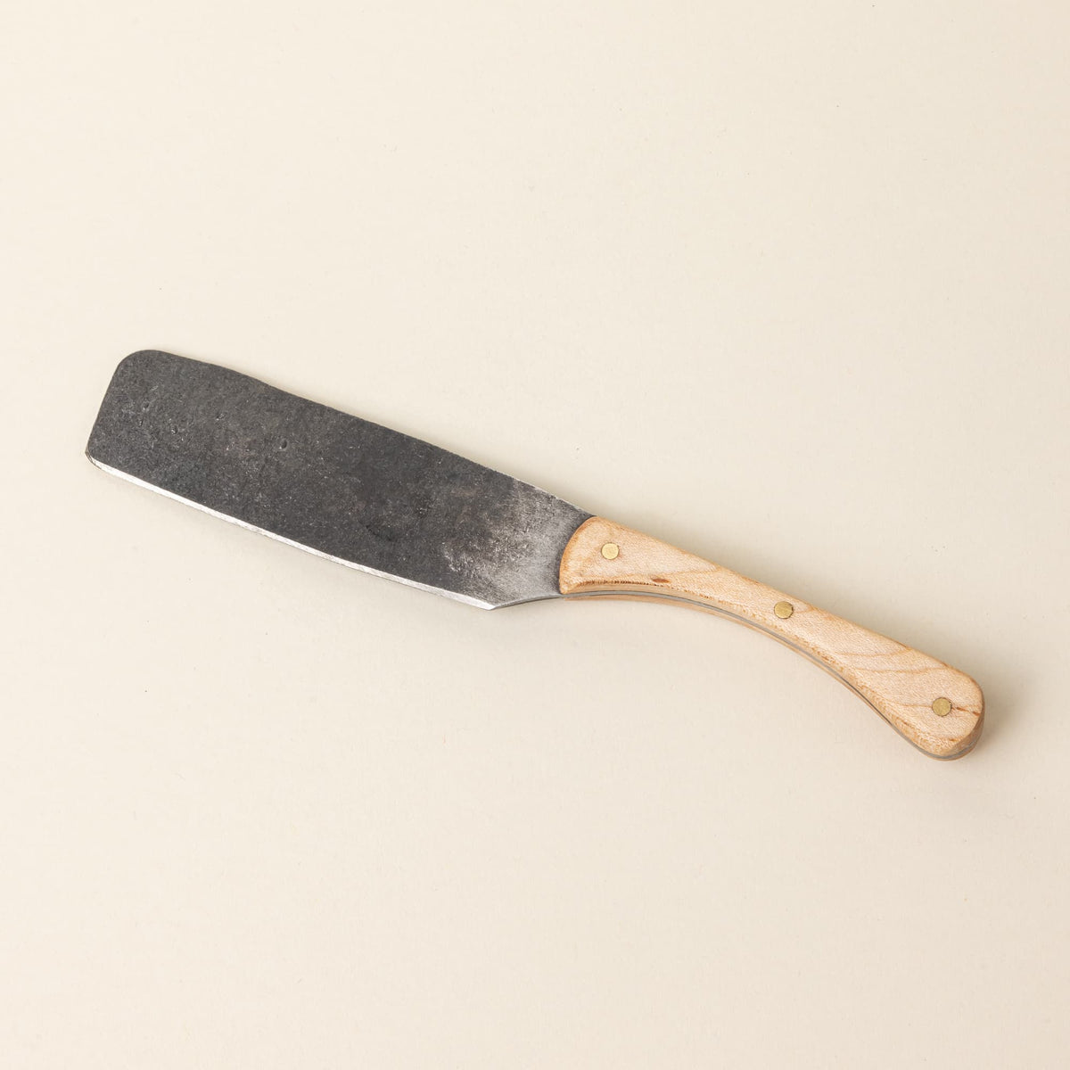 A hand-forged cheese knife with a stainless steel rectangular blade and a maple wood handle