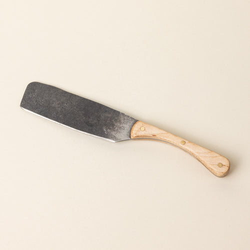 A hand-forged cheese knife with a stainless steel rectangular blade and a maple wood handle
