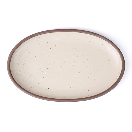 A large oval ceramic platter in a warm off-white color featuring iron speckles and an unglazed rim