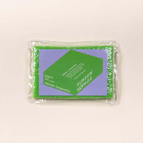 Green dishwashing sponge in clear packaging with a purple label reading “SUNSUN SPONGE” on a light background.