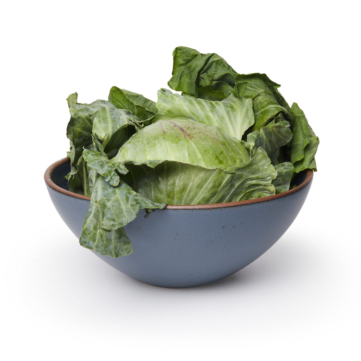A large ceramic mixing bowl in a cool, medium blue color featuring iron speckles and an unglazed rim, filled with lettuce