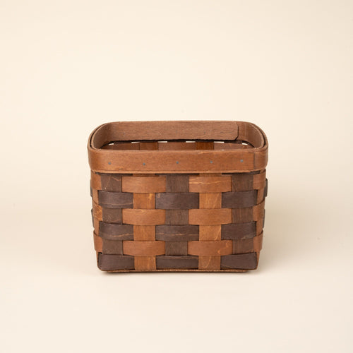Small rectangular woven wood basket in two-tone brown with an open top and reinforced rim, shown against a neutral background.