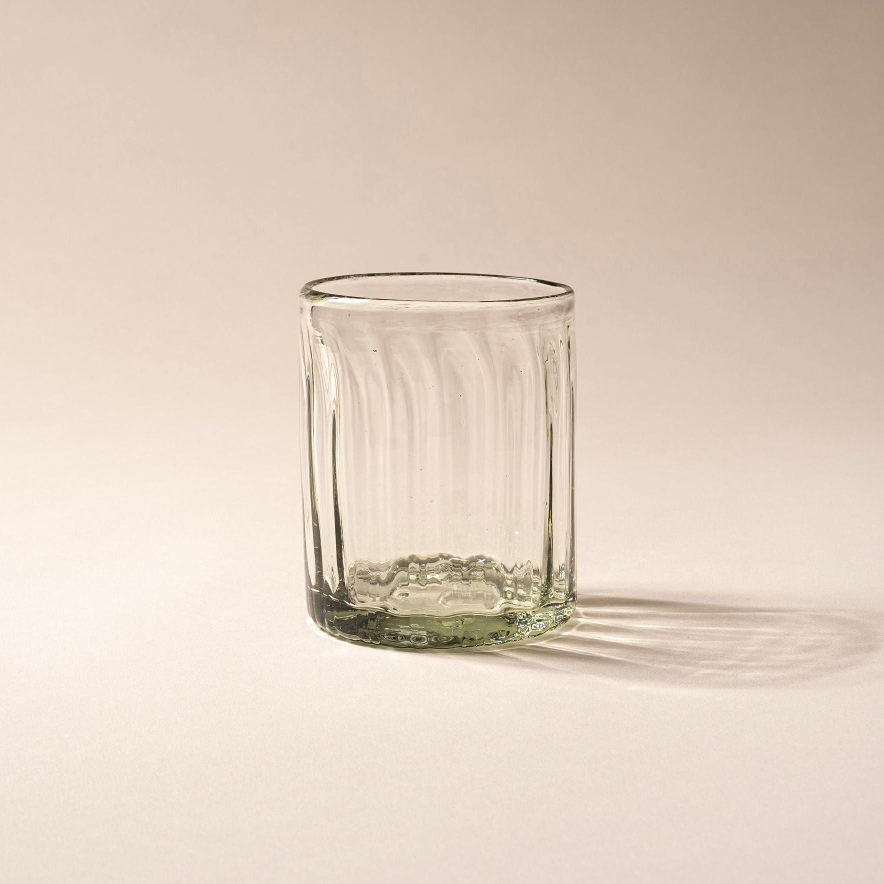 Taller clear textured glass tumbler with vertical ridges against a neutral background.