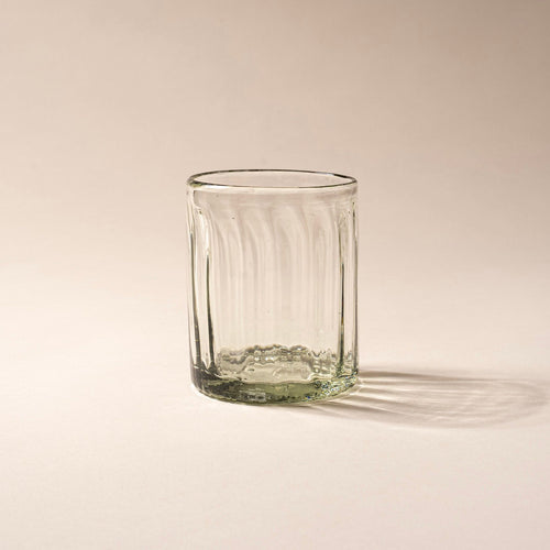Taller clear textured glass tumbler with vertical ridges against a neutral background.