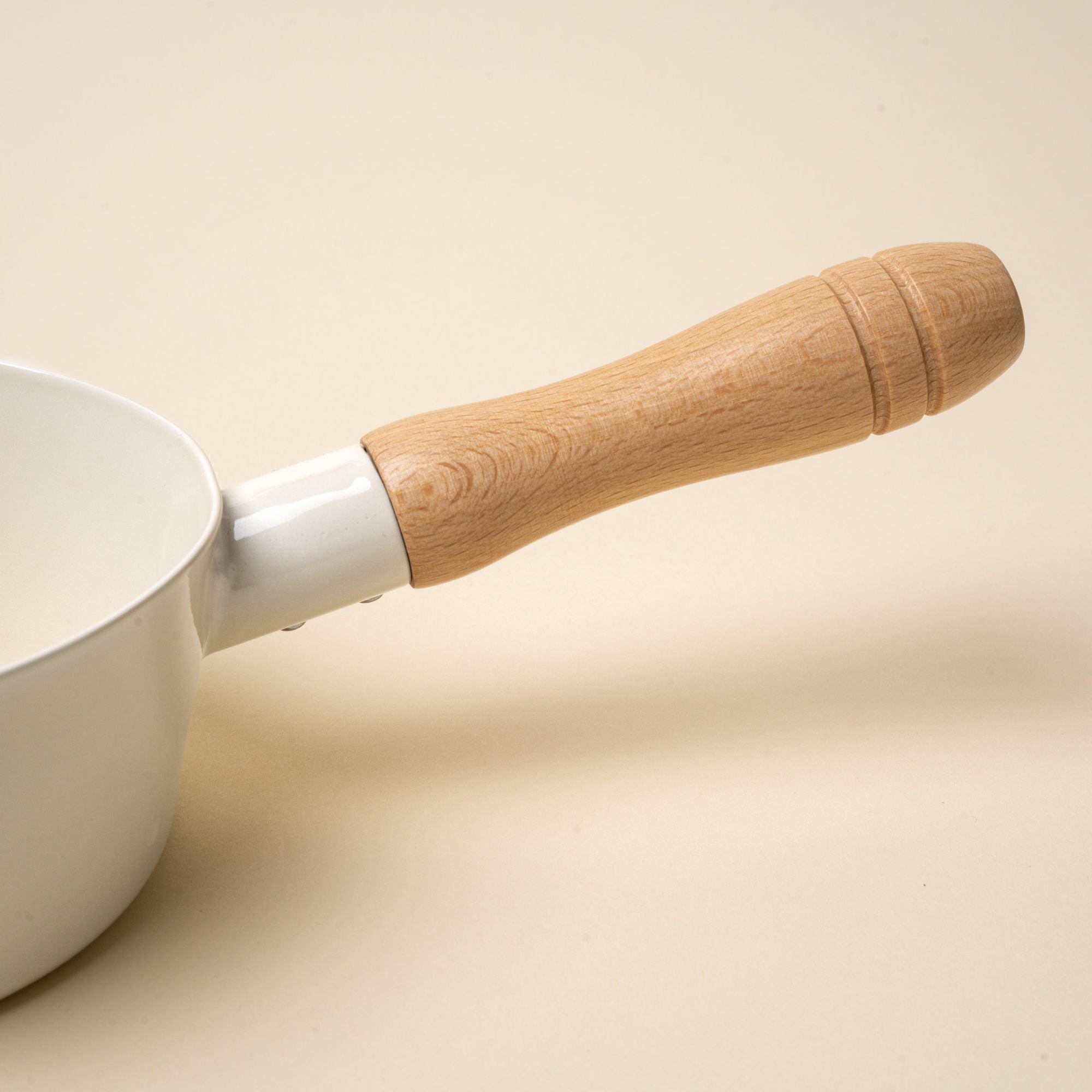 A closeup of a wooden handle on an enamel pot