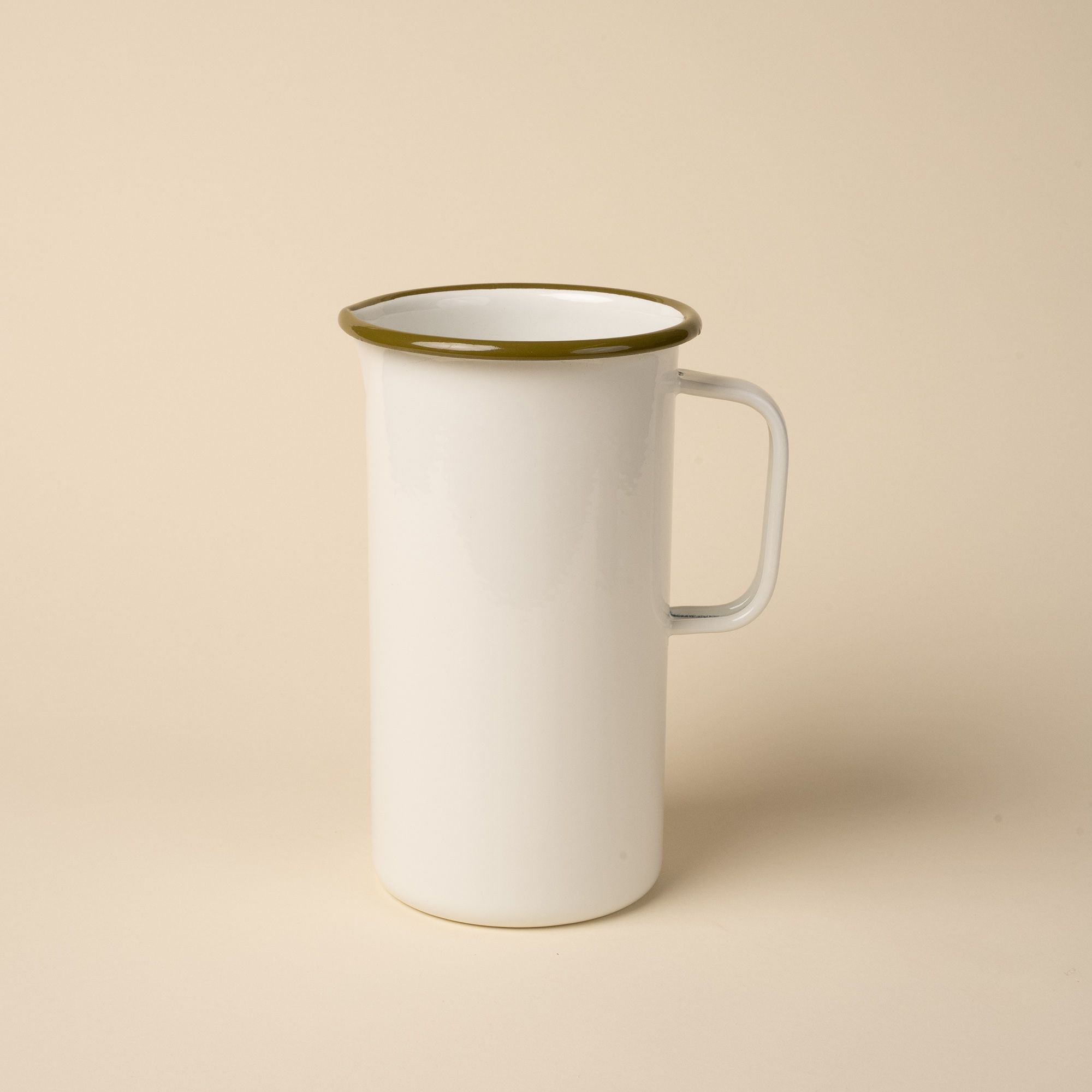 A large enamel pitcher with handle in a white color with an olive green rim.