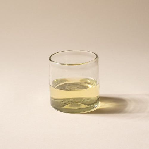 A short clear drinking glass, filled with white wine