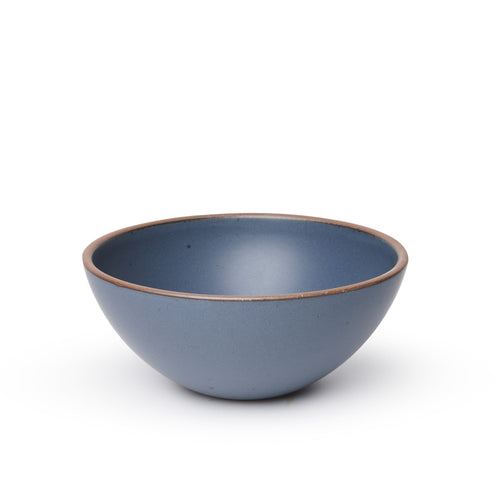 A large rounded ceramic bowl in a cool, medium blue color featuring iron speckles and an unglazed rim