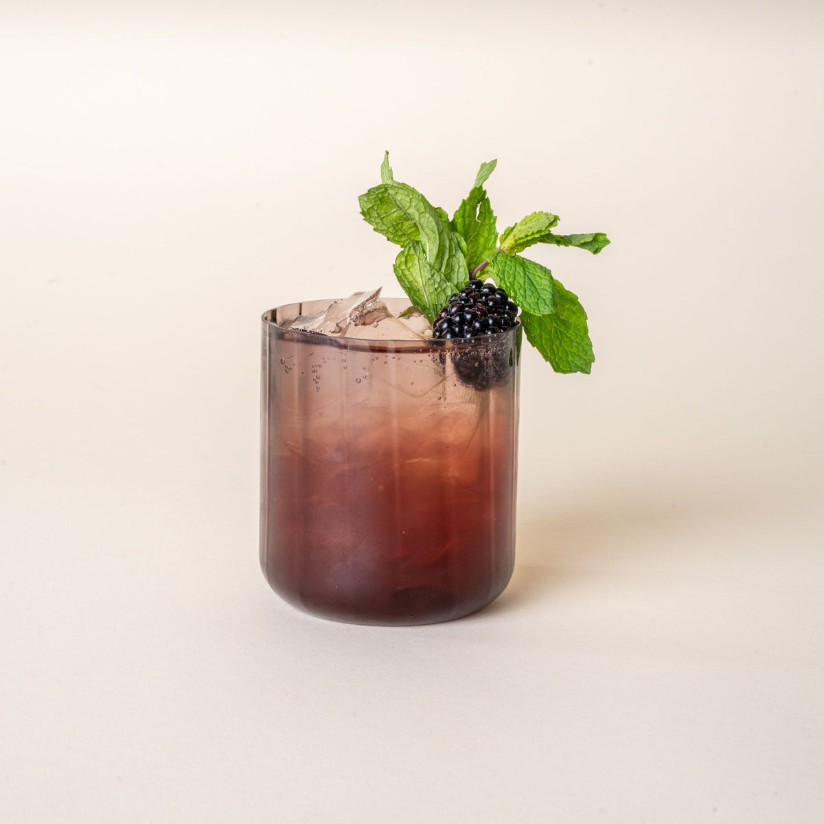 A cocktail in a fluted walled tumbler in a grey purple color