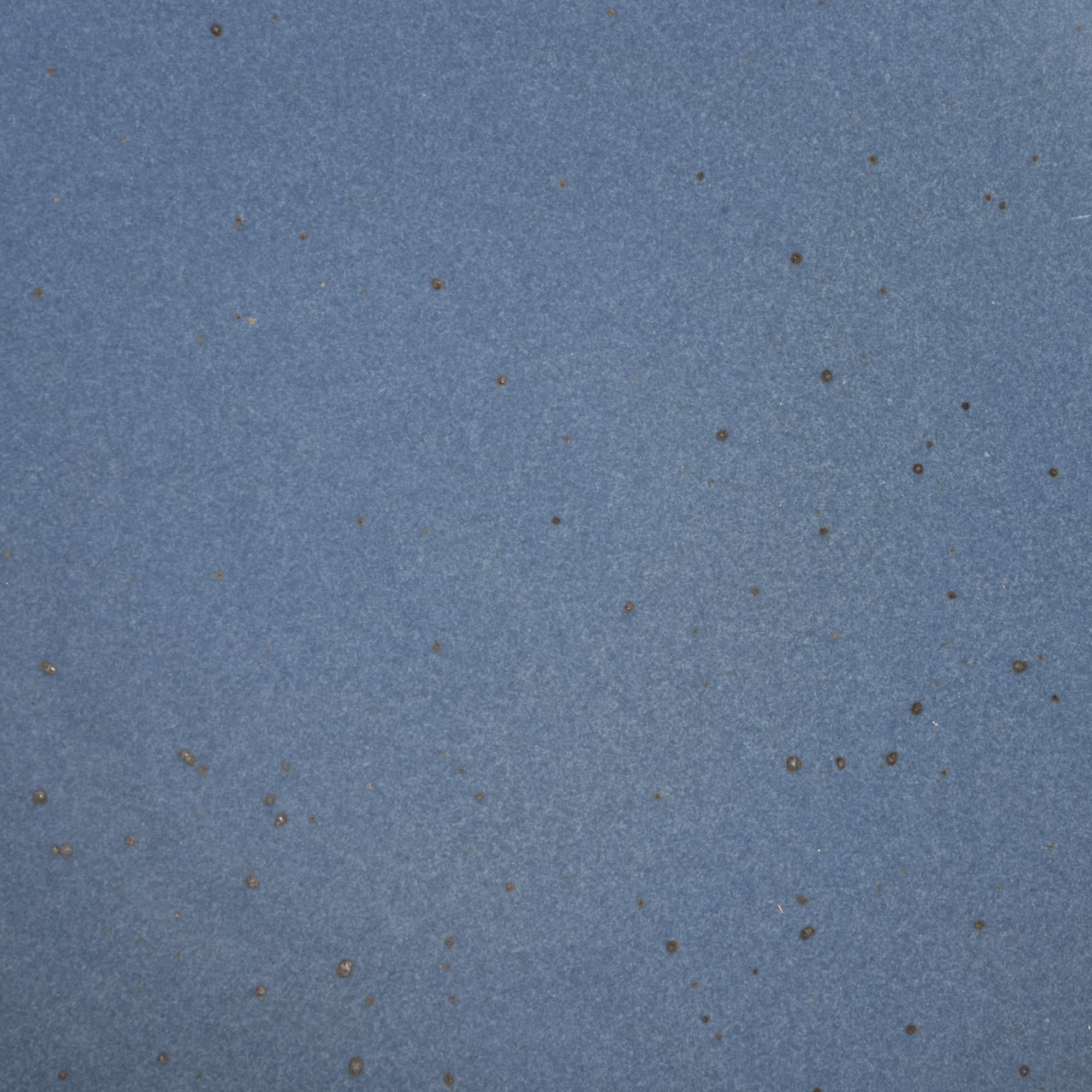 A closeup of a ceramic plate in a muted navy blue color with iron speckles throughout