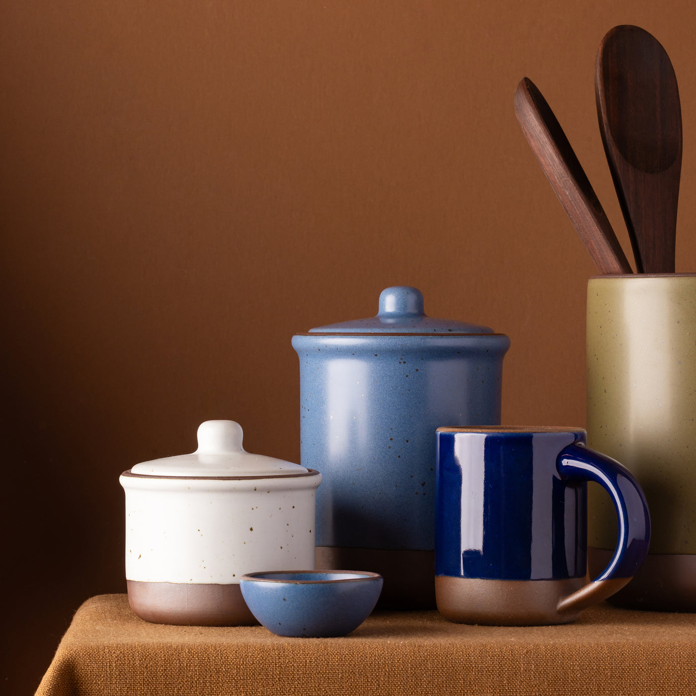 Ceramic Utensil Jar, Tall Jar, and Small Jar, Bitty Bowl and Mug all arranged on a tablecloth.