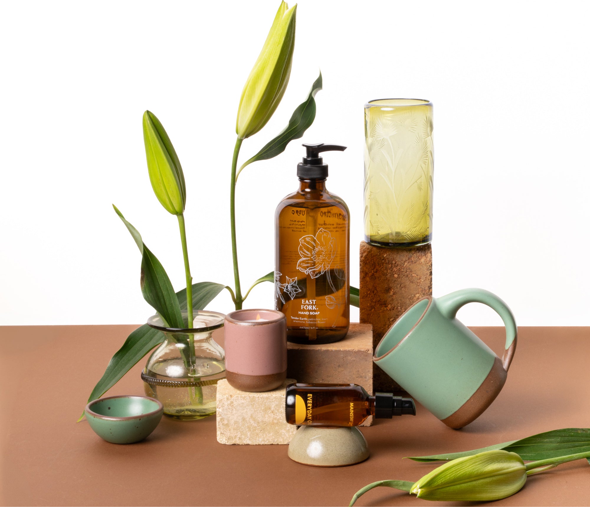 Collection of home decor items including bottles, a mug, and plants on a brown surface.