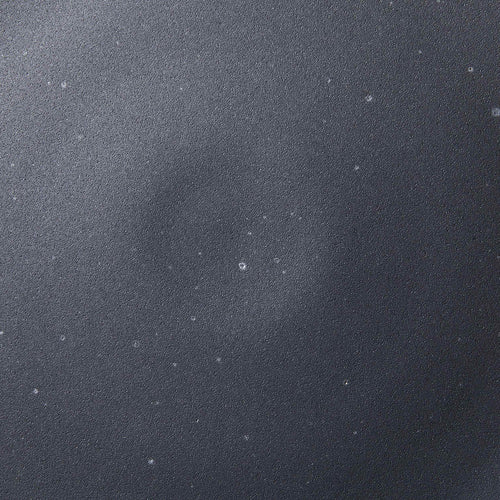 A closeup of a ceramic plate in a graphite black color with iron speckles throughout