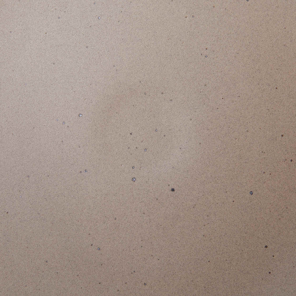 A closeup of a ceramic plate in a warm, pale brown color featuring iron speckles