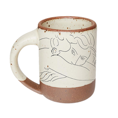 East Fork’s The Mug in a warm off white color with handle with a black decal of Henri Matisse’s Jeune femme la visage enfoui dans les bras, a bright blue, a line drawing of a young woman with face buried in her arms, on the body of the mug