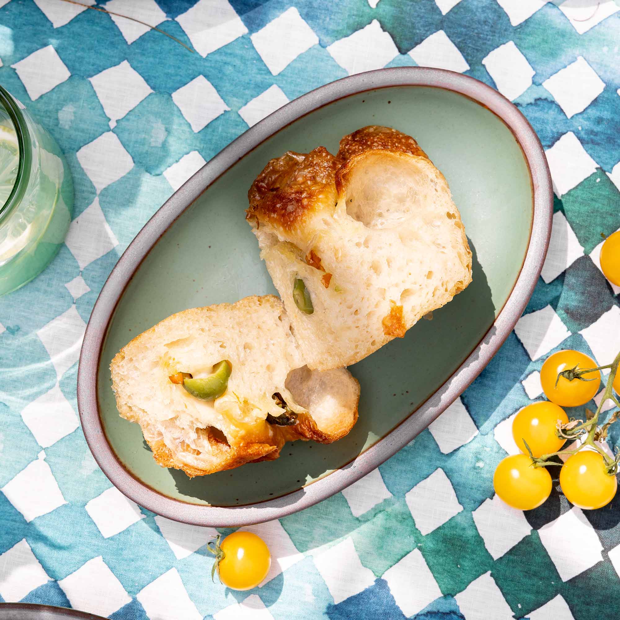 Bread slices with toppings on an oval green plate on a checkered tablecloth