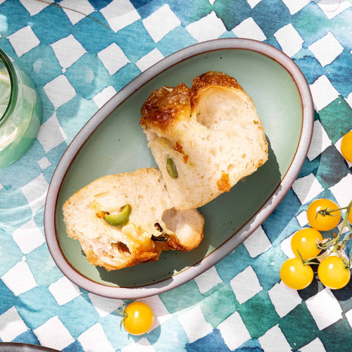 Bread slices with toppings on an oval green plate on a checkered tablecloth