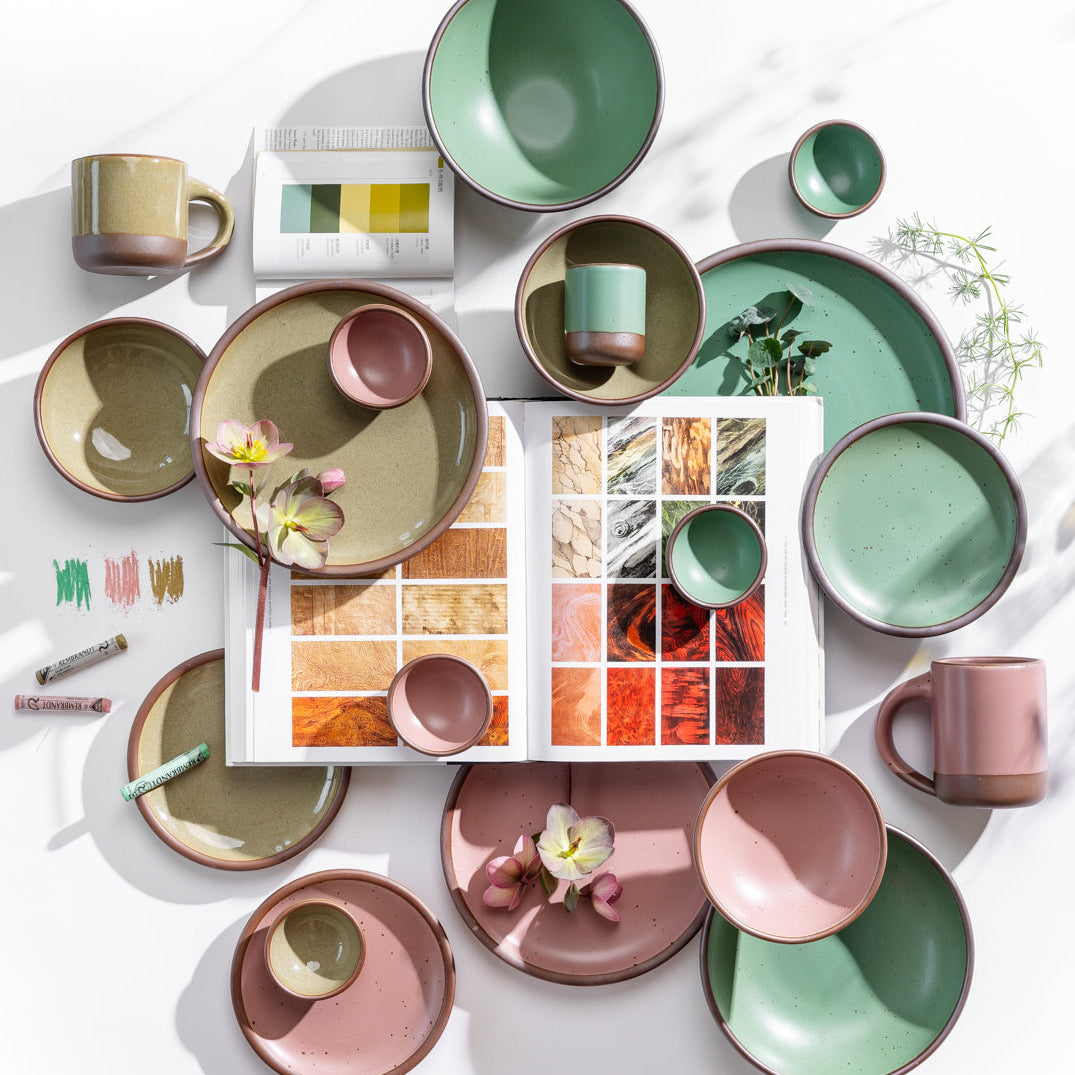 Colorful ceramic tableware on a white surface with a color swatch book open to pages showing color combinations.