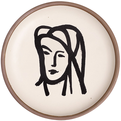 A ceramic plate featuring a decal of the artwork, Bédouine au grand voile, by Henri Matisse. A minimalist black ink decal of a woman's face wearing a large veil depicted by bold brushstrokes in an abstract, expressive style centered on an off-white ceramic plate with an unglazed rim.