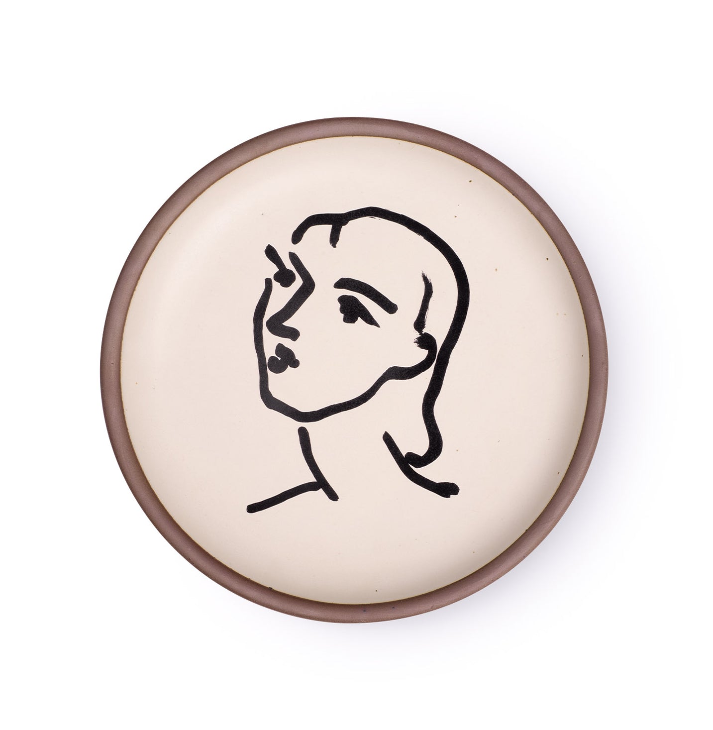 A ceramic plate featuring a decal of the artwork, Nadia aux cheveux lisses, by Henri Matisse. A minimalist black ink decal of a woman's face and neck in profile, facing left, in an abstract, expressive style centered on an off-white ceramic plate with an unglazed rim.