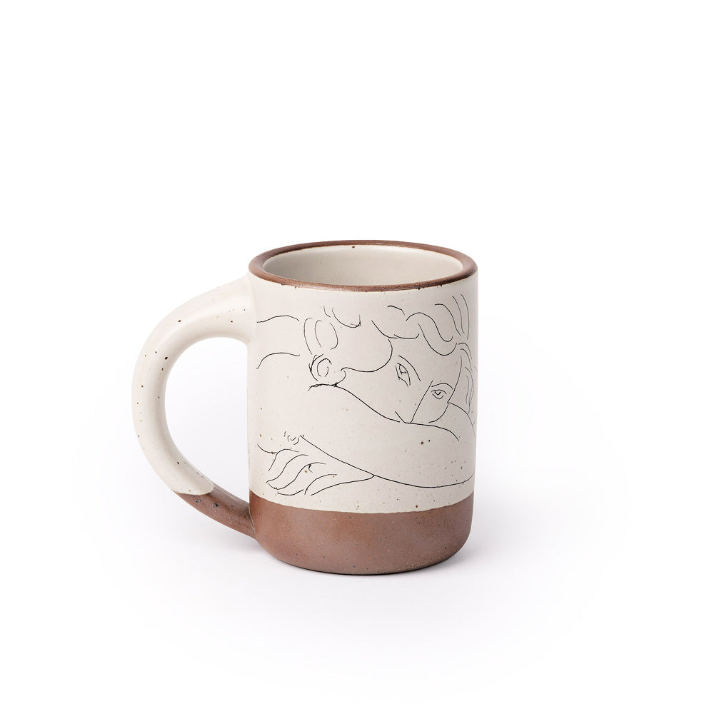 East Fork’s The Mug in a warm off white color with handle with a black decal of Henri Matisse’s Jeune femme la visage enfoui dans les bras, a bright blue, a line drawing of a young woman with face buried in her arms, on the body of the mug
