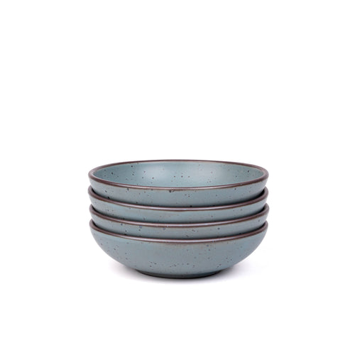 A stack of 4 dinner-sized shallow ceramic bowls in a blue-grey color featuring iron speckles and an unglazed rim