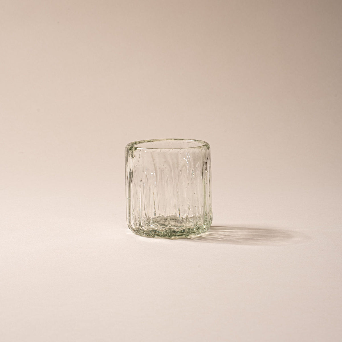Clear textured glass tumbler with vertical ridges against a neutral background.