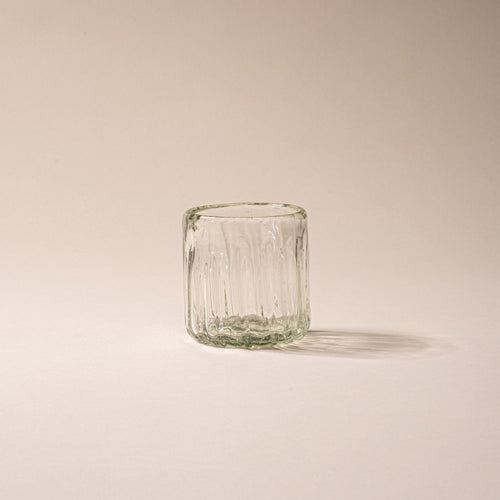 Clear textured glass tumbler with vertical ridges against a neutral background.