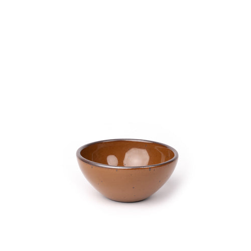 A small dessert sized rounded ceramic bowl in a glossy caramel brown color featuring iron speckles and an unglazed rim