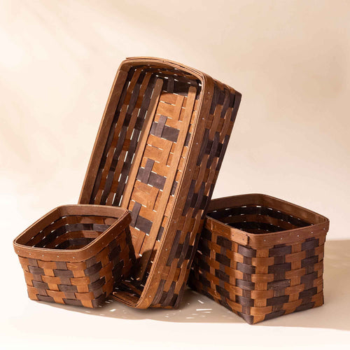 Set of three woven wooden storage baskets in different sizes with a two-tone pattern.