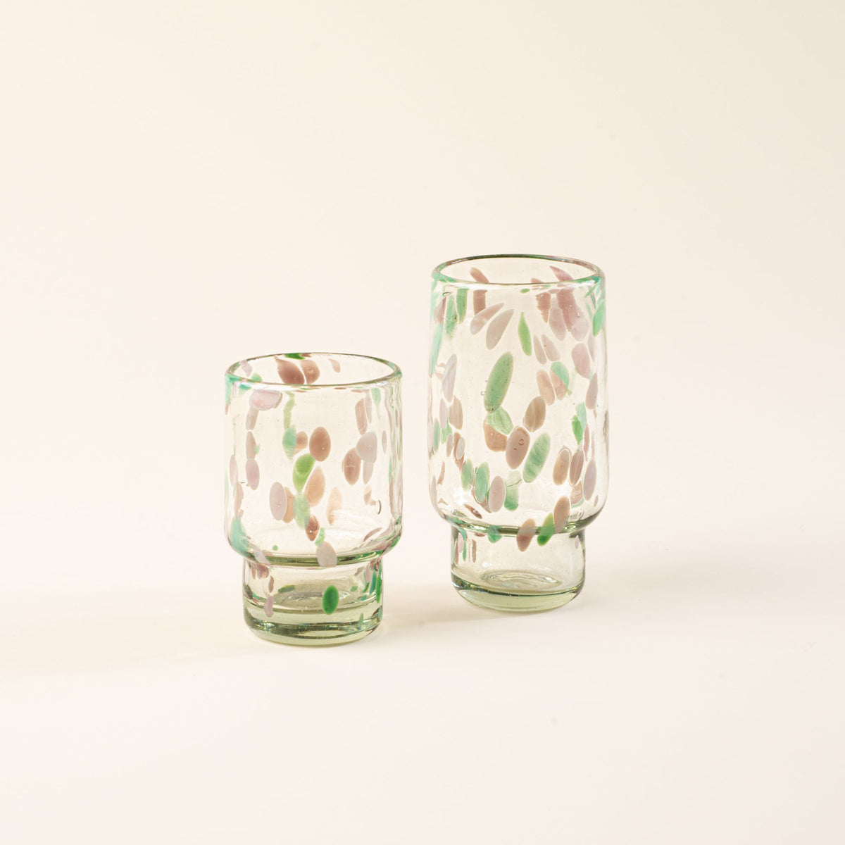Short and tall clear glasses with pastel green and pink speckled patterns