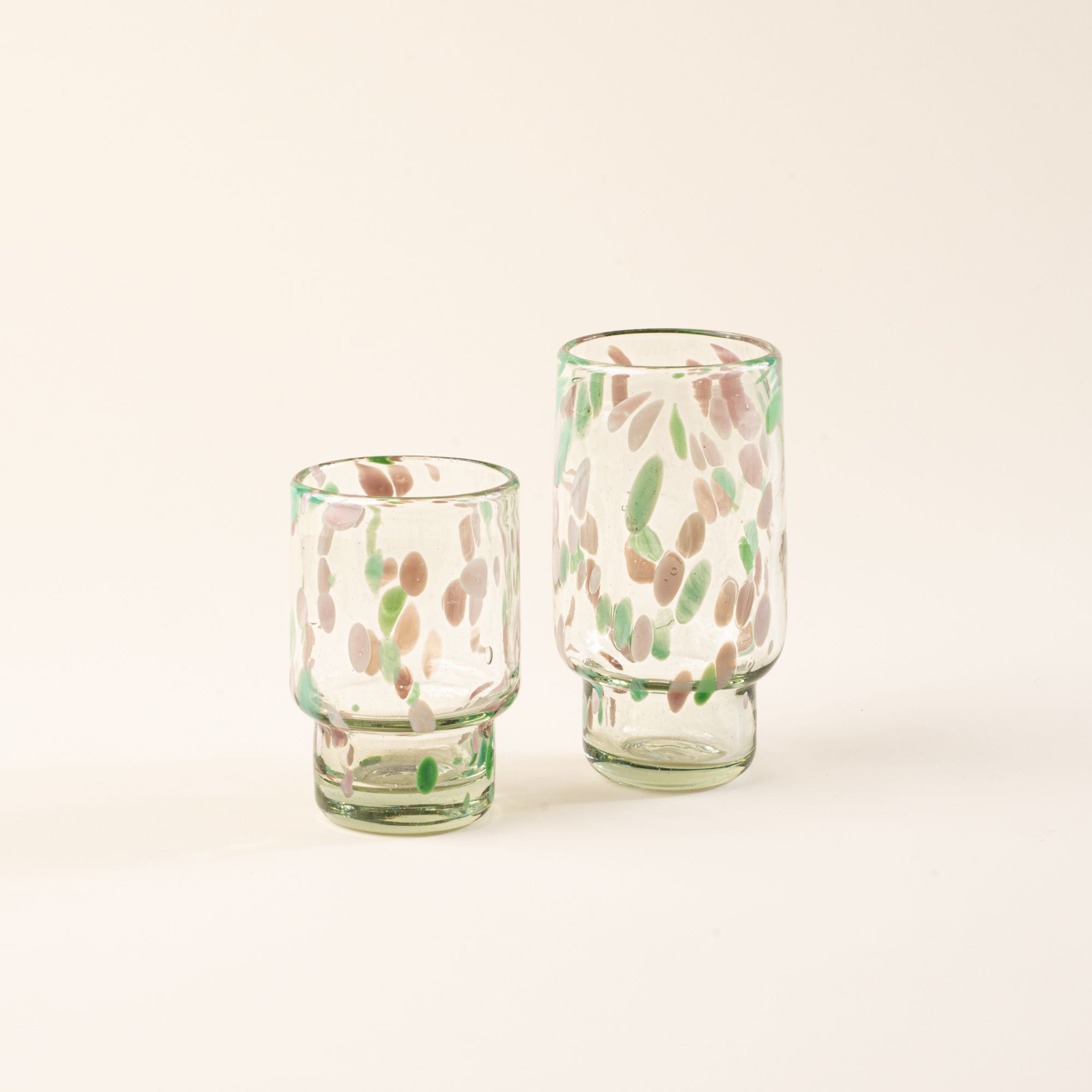 Short and tall clear glasses with pastel green and pink speckled patterns