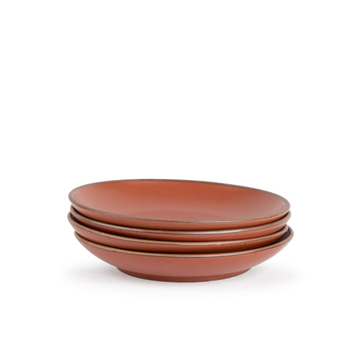 A stack of 4 large ceramic plates with a curved bowl edge in a cool burnt terracotta color featuring iron speckles and an unglazed rim.