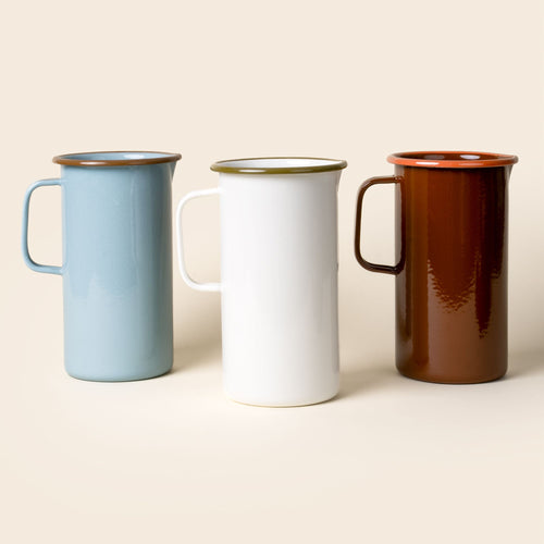 Three enamel pitchers with handles in a row - a robin's egg blue, white, and red-brown color.