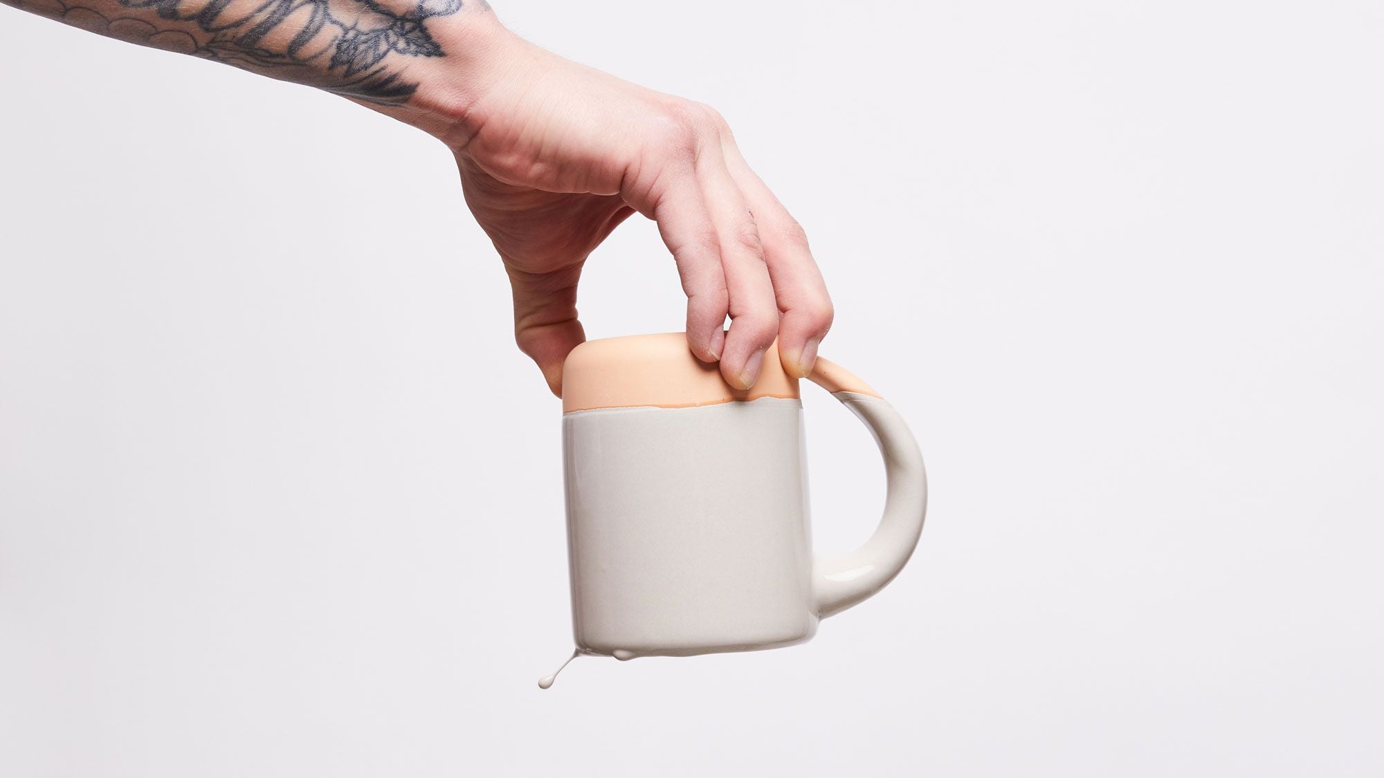 A hand holds the East Fork Mug upside down to glaze it, glaze is dripping off the rim.