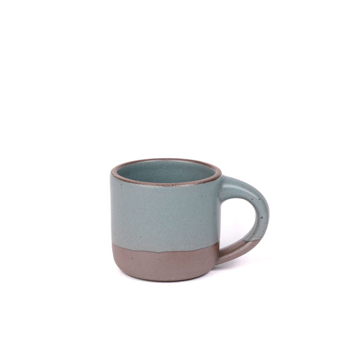 A small sized ceramic mug with handle in a blue-grey yellow featuring iron speckles and unglazed rim